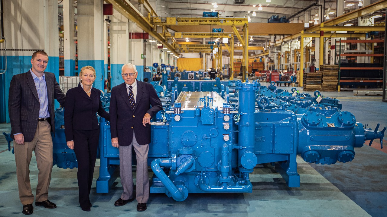 Jim Buchwald, Karen Wright, and Alex Wright stand next to Ariel's 40,000th compressor within their manufacturing complex.