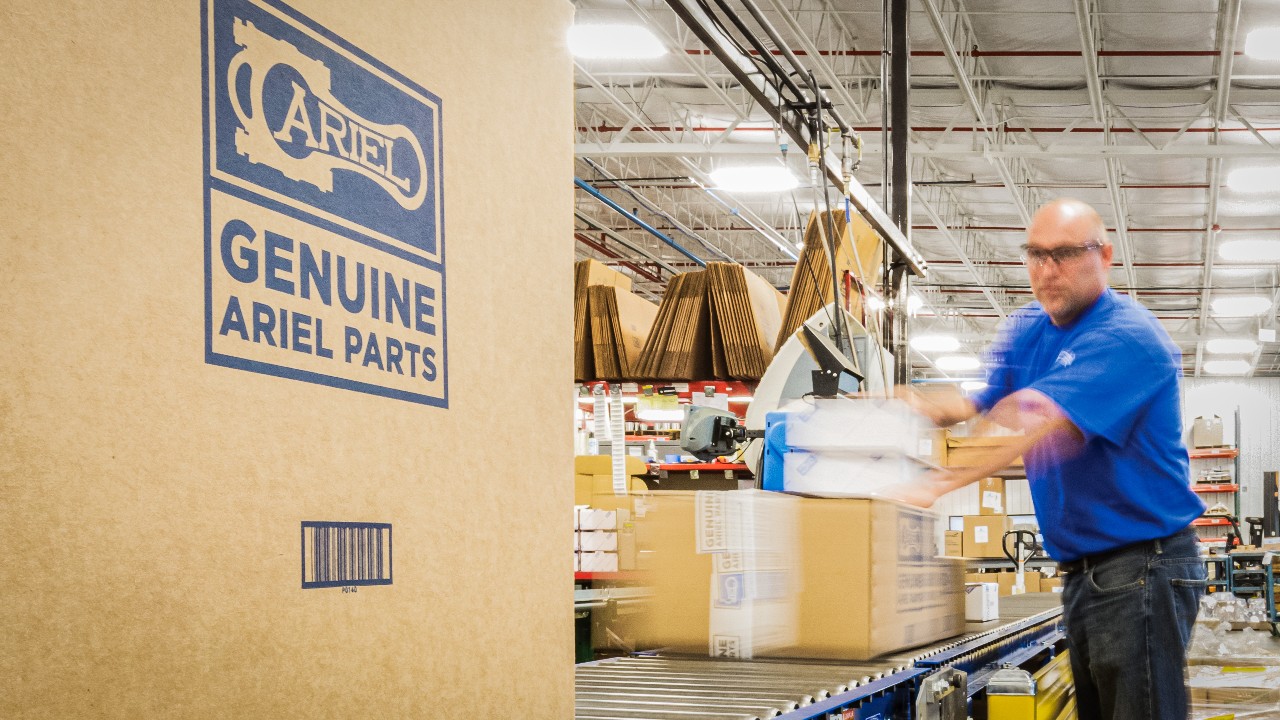 An employee pushing a box of Ariel parts down a conveyer belt