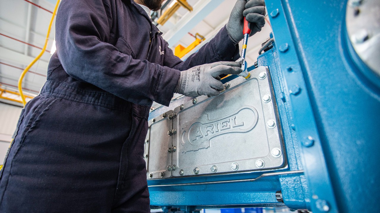 A training mechanic removing the side guide door on an Ariel compressor with a socket wrench